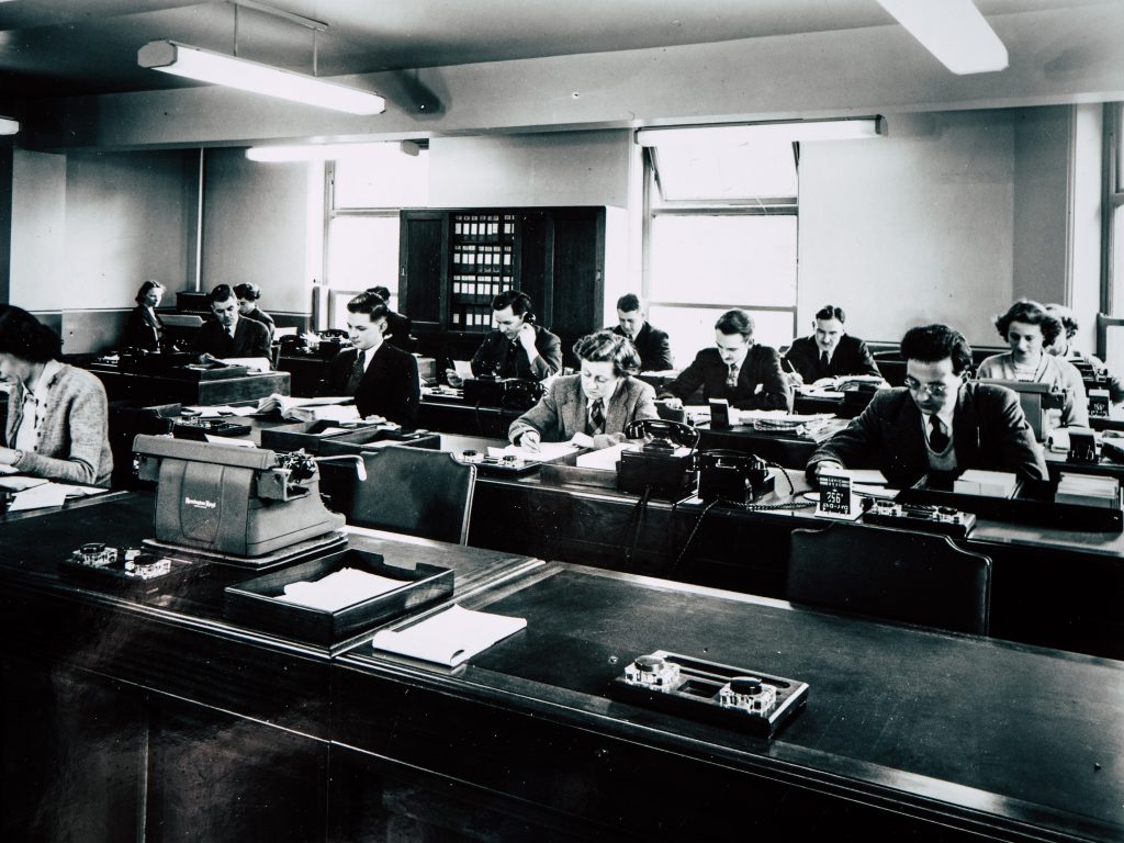 A vintage photograph showing a room filled with workers from 1951. Photo by Chris Curry on Unsplash.