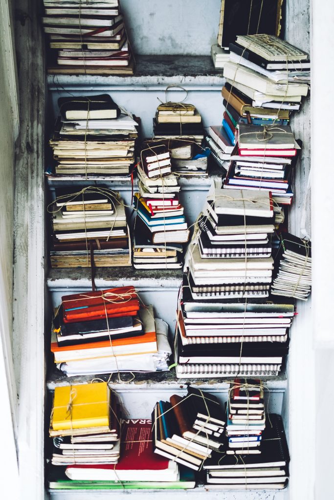 Bound journals tied in stacks with twine placed on steps in a stairwell