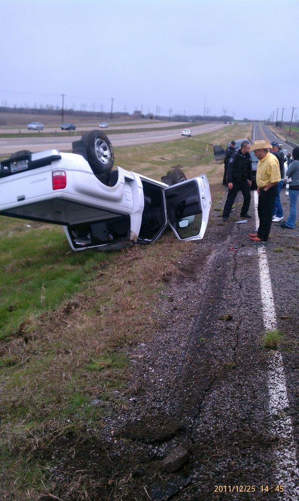 A white pickup truck overturned in a median with bystanders, dated 2011/12/25