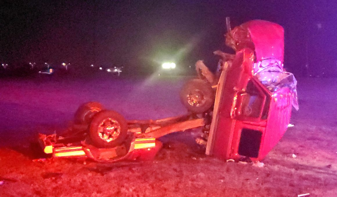 Image of wrecked truck / accident wreckage on grass at nighttime.