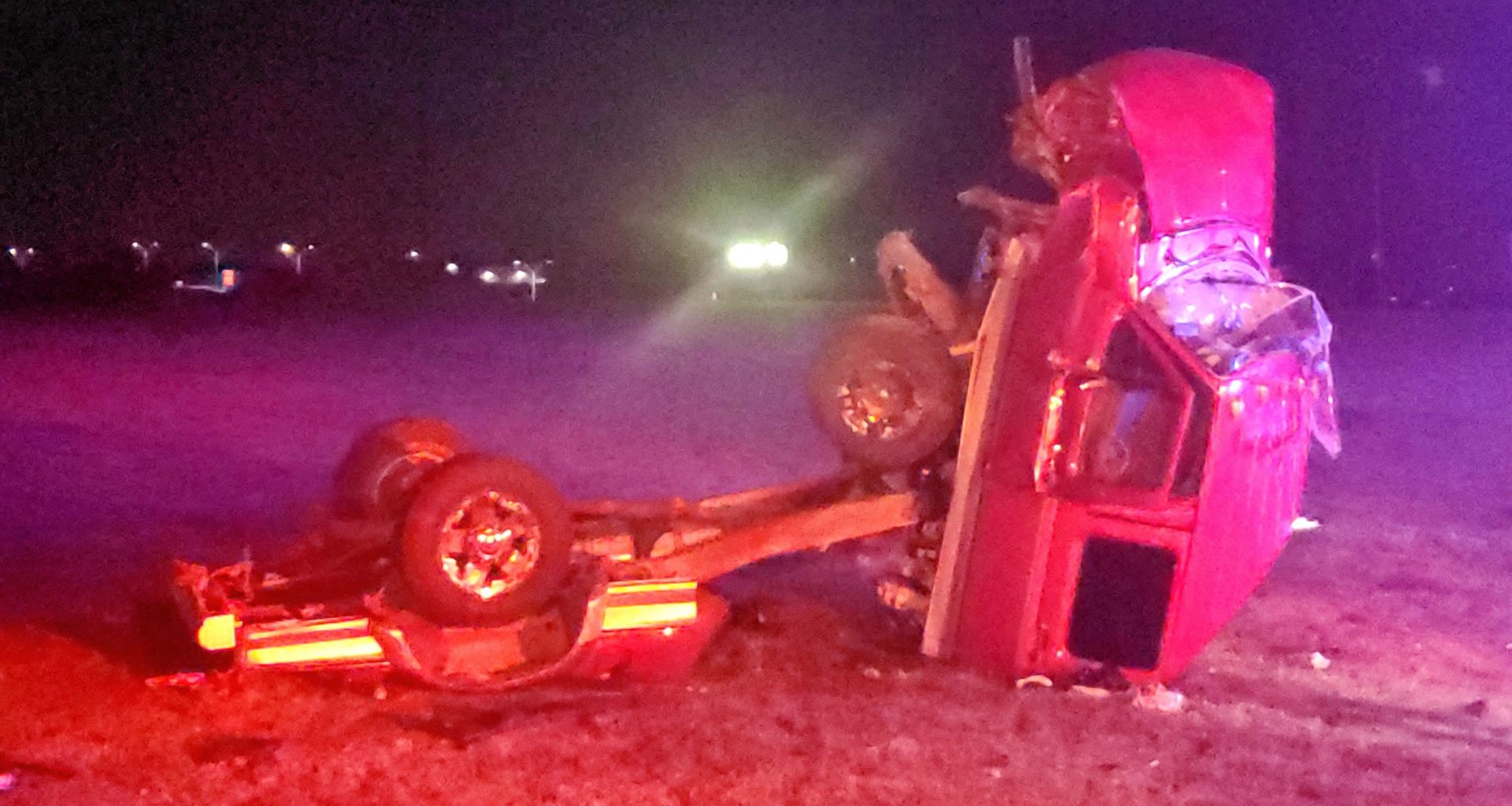 Image of wrecked truck / accident wreckage on grass at nighttime.