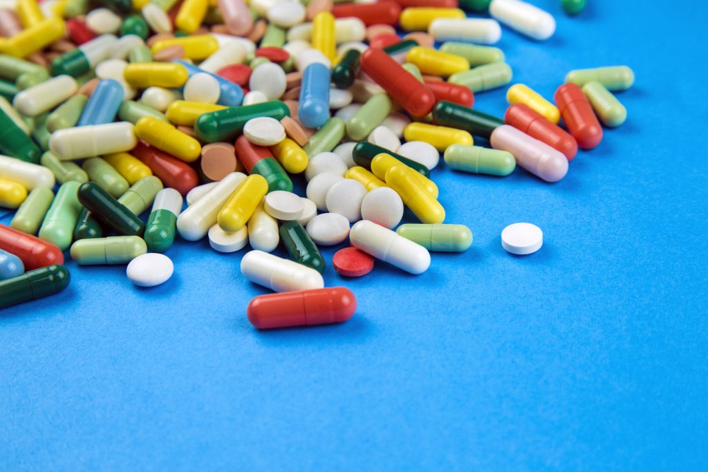 Lot of colorful pills on a blue background - depositphotos.com