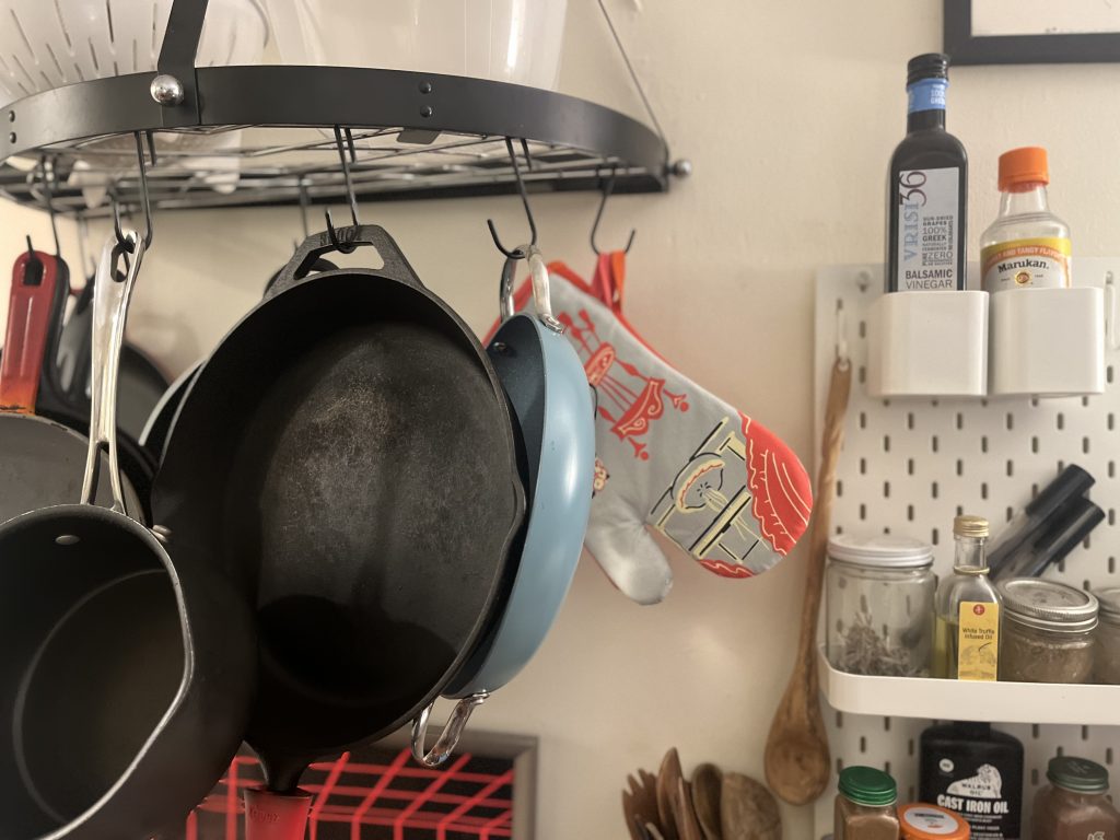 A photo of hanging pots, oven mitts, cooking oils, spices and utensils